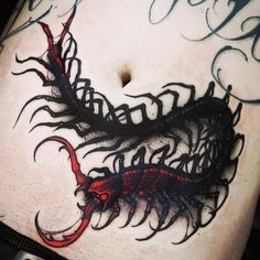 an artistic tattoo design on the side of a man's stomach, with black and red ink