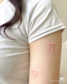 a woman's arm with a bow tattoo on the left side of her arm