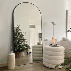 a large mirror sitting on top of a wooden floor next to a christmas tree in a living room