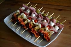 several skewers of meat and vegetables are on a white plate with toothpicks