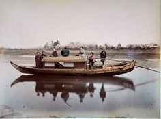 a group of people standing on the back of a small boat in shallow water near shore