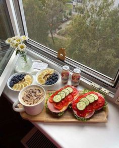 a sandwich with cucumbers, tomatoes, avocado and other toppings on a cutting board