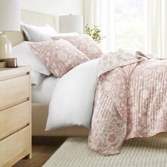 a bed with pink and white comforters in a bedroom