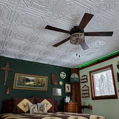 a bed room with a neatly made bed and a ceiling fan in the middle of it