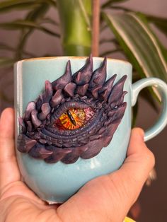 a hand holding a coffee cup with an eye in the center and flowers on it