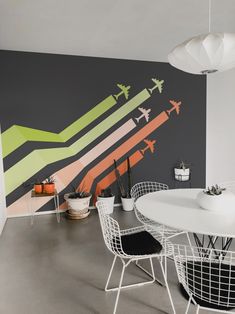 a white table and chairs sitting in front of a wall with airplanes painted on it