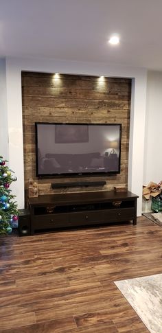 a flat screen tv sitting on top of a wooden entertainment center next to a christmas tree