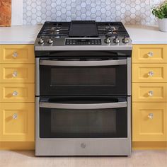 two ovens side by side in a kitchen with yellow cabinets and white counter tops