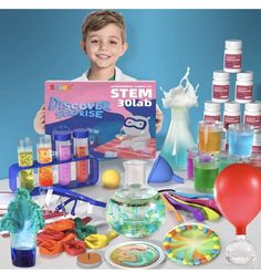 a young boy holding up a sign surrounded by science supplies