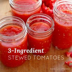 four jars filled with red sauce sitting on top of a wooden table