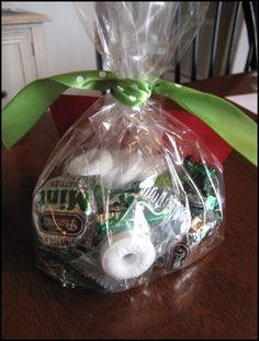 a bag filled with lots of different items on top of a wooden table next to a green ribbon