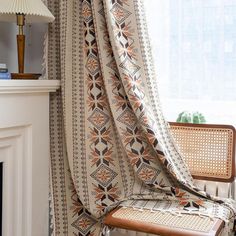 a chair sitting in front of a fire place next to a window with curtains on it