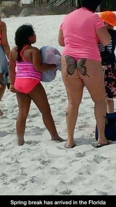 three women in bikinis on the beach, one is holding a suitcase and another has her back turned to the camera