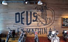 several motorcycles are parked in front of a wooden wall with the words deus on it