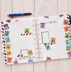 an open planner with stamps on it next to a pen