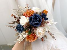 a bridal bouquet with blue, orange and white flowers is held in someone's hand