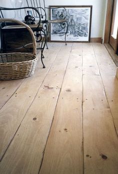 a wooden floor in a room with pictures on the wall and a wicker basket next to it