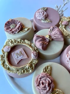 some pink and gold decorated cookies on a white plate