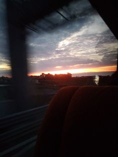 the sun is setting in the distance as seen from inside a bus window with dark clouds