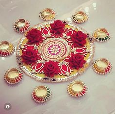 a decorated plate with red roses and candles on it, surrounded by other plates in the middle