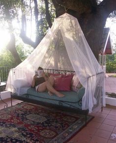 a woman sitting on top of a bed under a tree