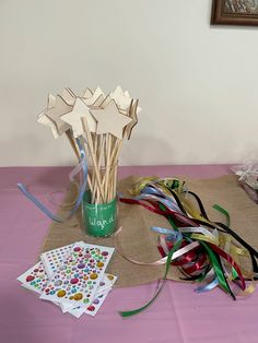 a vase filled with paper stars and streamers on top of a pink table cloth