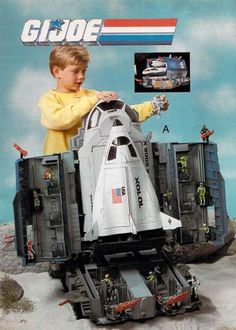 a young boy is playing with a toy space shuttle in front of an advertisement for gijoe