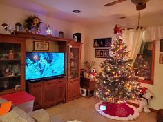 a living room with a christmas tree in front of the tv and decorations on the wall