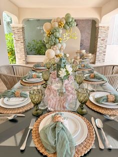 a table set with plates, silverware and green napkins