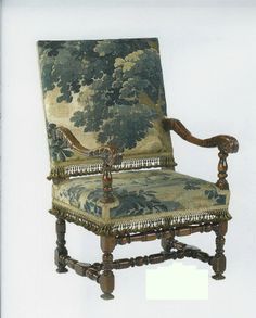 an antique chair with tapestryed upholstered back and arm rests against a white wall