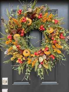 a wreath on the front door with berries, pine cones and other autumn foliages