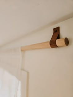 a close up of a wooden object on a wall near a curtain rod and window