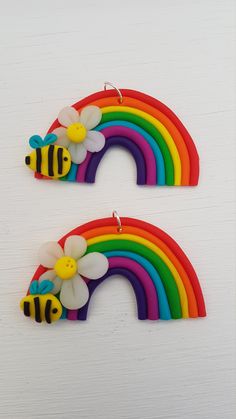 two rainbows with flowers and bees on them are sitting in front of a white wall