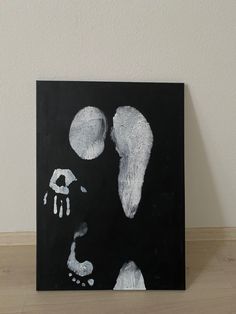 a black and white painting on a wooden floor next to a wall with an image of a human handprint