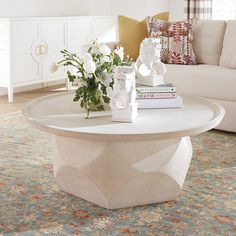 a living room with white furniture and flowers on the coffee table