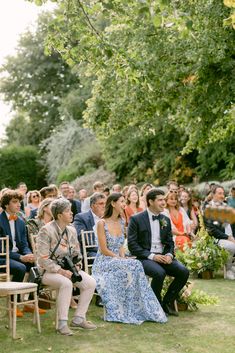 a group of people sitting on chairs in front of each other at a wedding ceremony