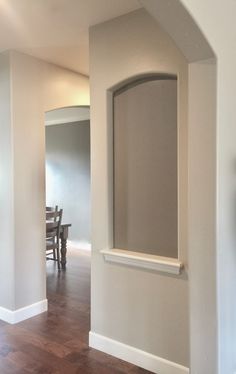 an empty living room with hard wood flooring and white paint on the walls, along with a wooden table and chairs