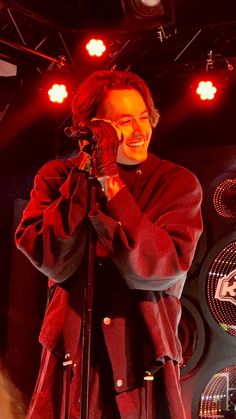 a man standing in front of a microphone on top of a stage with red lights