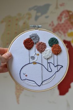 a hand is holding a embroidery hoop with an image of a whale and flowers