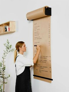 a woman writing on a wall with a large roll of paper