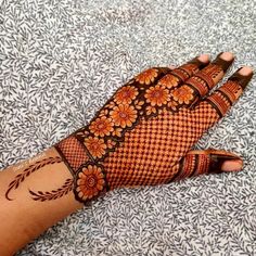 a woman's hand is decorated with hennap and orange flower designs on it