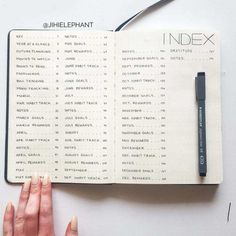 a hand holding a pen over an index book