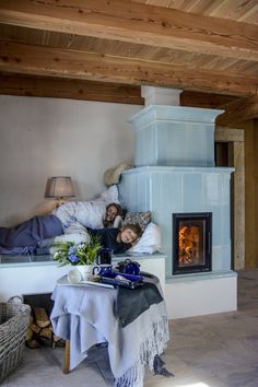 a person laying in bed next to a fire place with a blanket on top of it