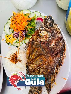 a white plate topped with fish next to rice and veggies