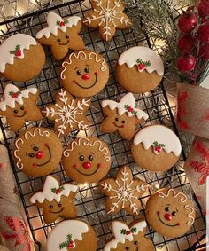 cookies decorated with icing and snowflakes are on a cooling rack next to christmas decorations