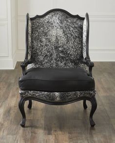 a black and white chair sitting on top of a hard wood floor next to a wall