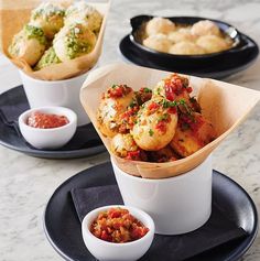 three plates with different types of food in them on a marble counter top, one is white and the other is black