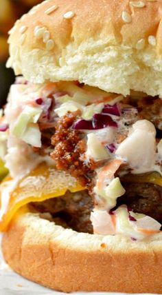 a close up of a hamburger on a bun with coleslaw and mustard in the middle