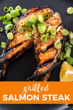 grilled salmon steak on a black plate with green onions