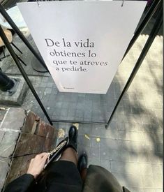 a person sitting on the ground with their feet up next to a sign that says de lavidda objetes lo que to atreves a pedrifie